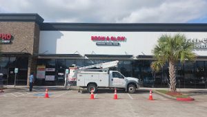 Truck installing a sign at Brow & Glow store, showcasing building signs Houston services for professional signage.