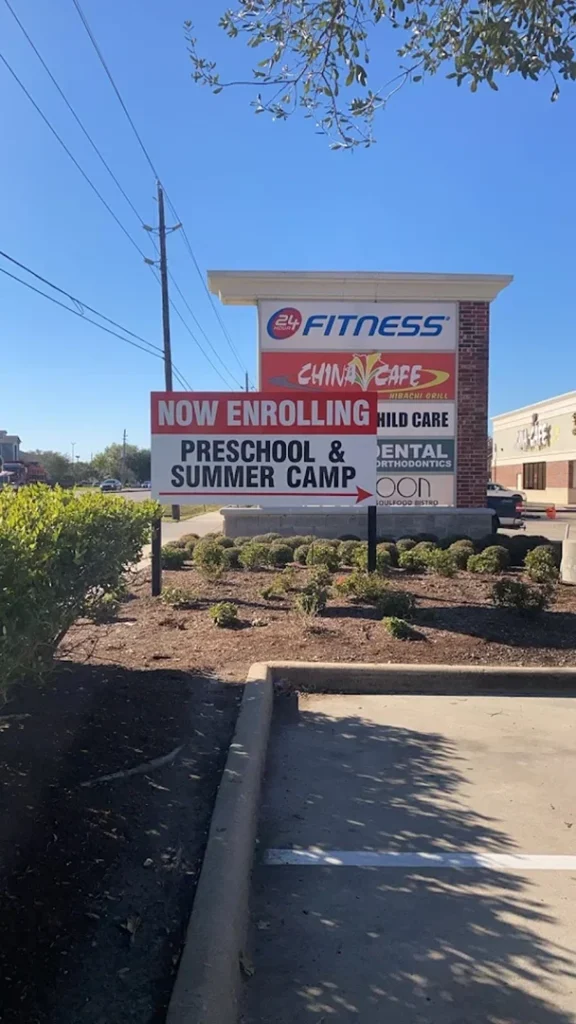 Promotional sign for preschool and summer camp enrollment, crafted by a Houston sign company, displayed outside a fitness center.