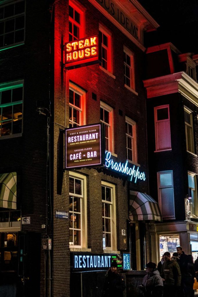Custom red neon LED channel letter 'STEAK HOUSE' sign manufactured and installed by a Houston sign manufacturing company, brilliantly illuminated on a brick building at night.