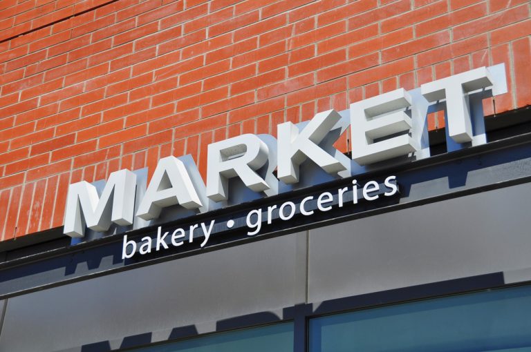 3D white dimensional letters for a MARKET storefront against a brick wall, showcasing quality business signs Houston services.