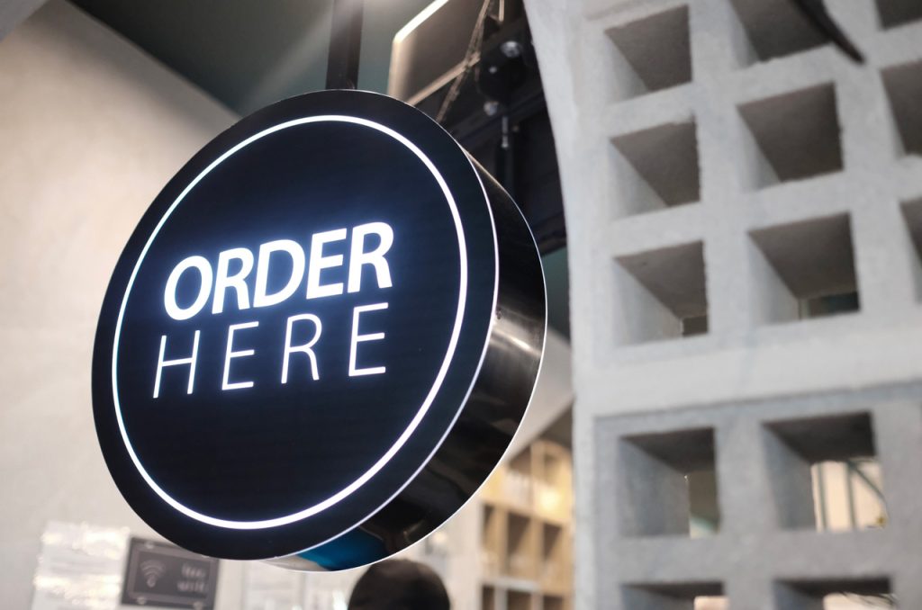 Circular black LED 'ORDER HERE' sign with a white illuminated border, a modern example of interior business signs Houston.