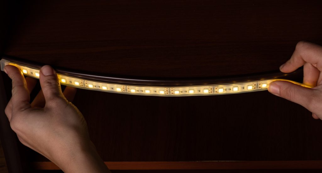 A close-up of a Houston sign installation expert precisely aligning waterproof LED lighting for a custom cabinet.