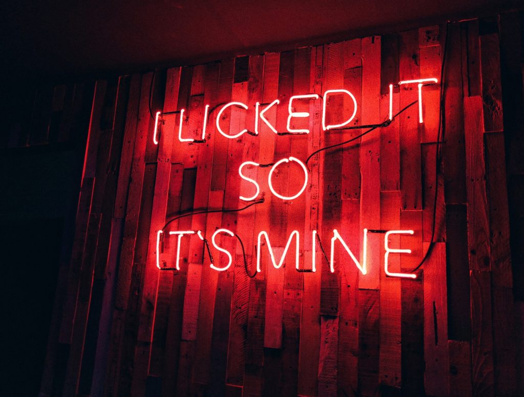 Red neon quote sign on wood wall, an example of trendy indoor custom signs Houston companies use for decor.