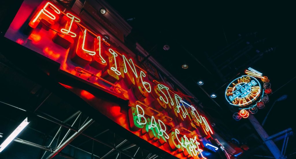 Vibrant neon outdoor signs for businesses Houston, featuring the colorful Filling Station Bar and Café signage.