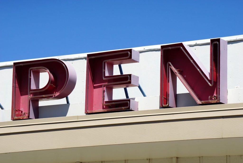 Close up of red custom neon channel letters by a sign manufacturer Houston for an open business storefront sign.