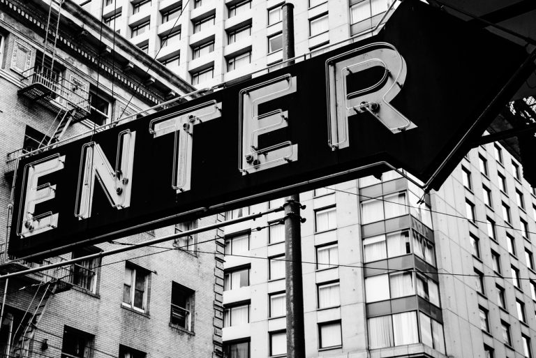 Black and white photography of a large vintage ENTER arrow building signs Houston against a city skyscraper backdrop.