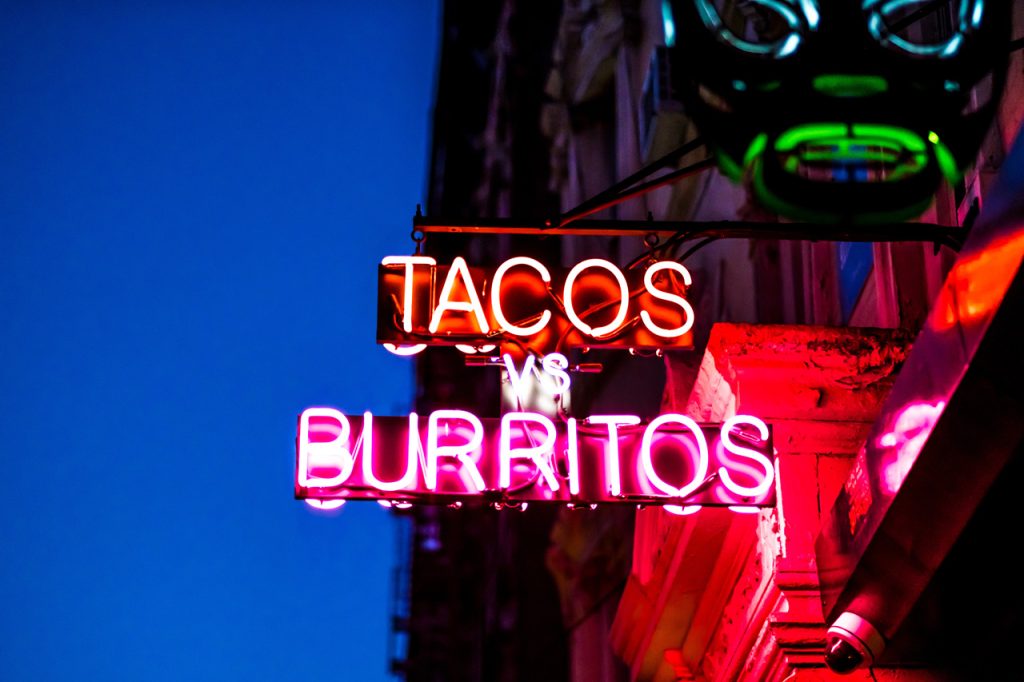 Custom neon blade sign for a restaurant by a sign manufacturer Houston, featuring glowing pink and orange neon tubes.