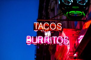 Custom neon blade sign for a restaurant by a sign manufacturer Houston, featuring glowing pink and orange neon tubes.