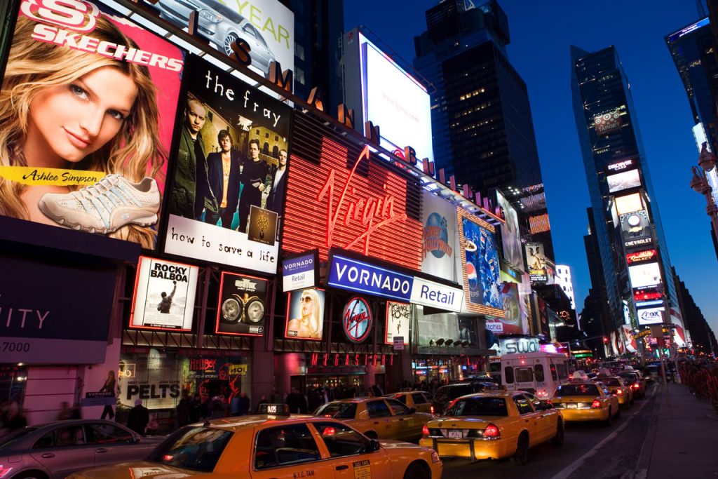 Iconic yellow cabs drive past large Houston commercial signs and banking billboards in a glowing city center.