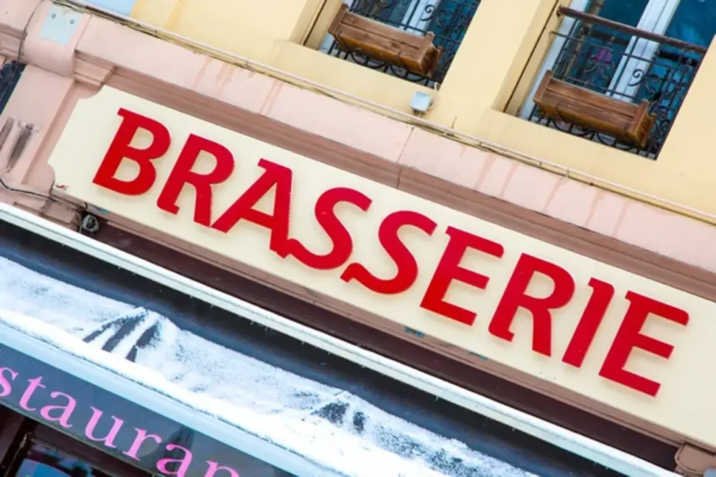 Red Brasserie lettering on a building facade, showcasing high-quality houston commercial signs for local restaurants.
