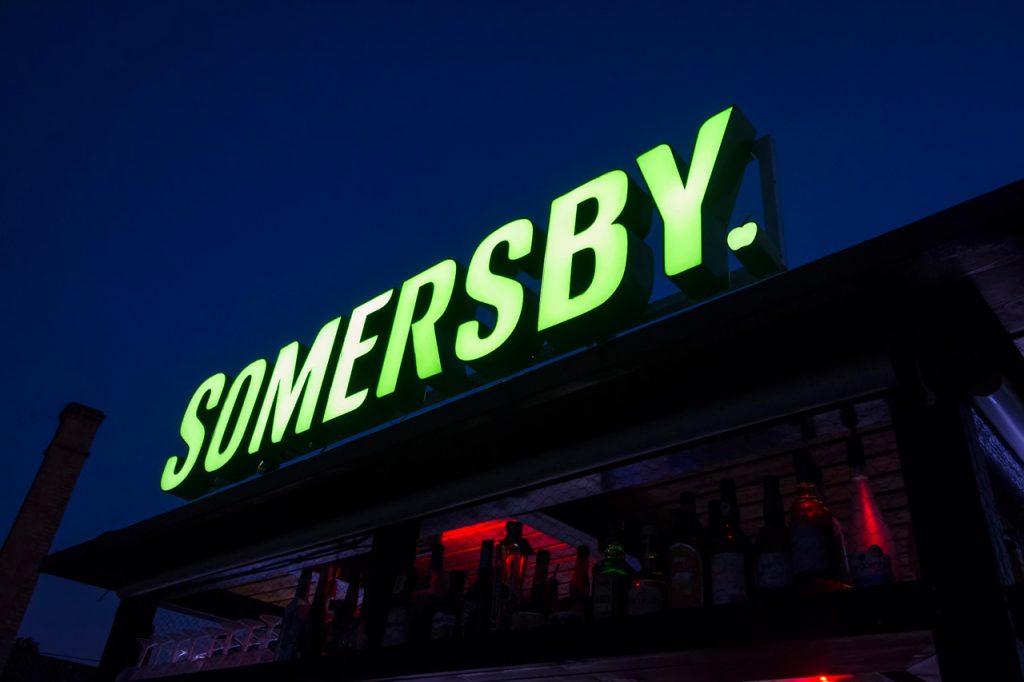 Custom LED channel letters for Somersby by a sign manufacturing Houston expert, featuring vibrant green outdoor branding.