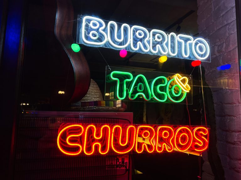 Multi-color neon window display of burritos and tacos crafted by a sign manufacturer Houston for a vibrant eatery.