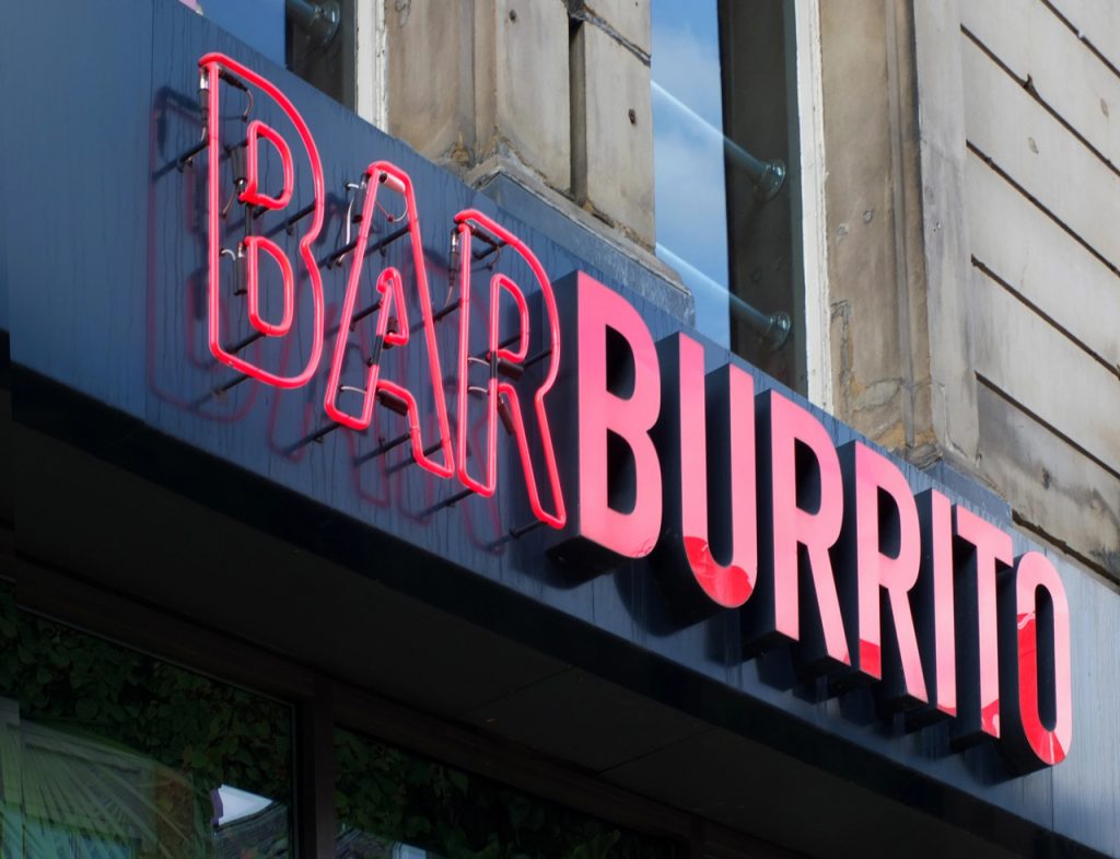 Red neon channel letter fabrication by a sign manufacturer Houston on a modern black storefront for a burrito shop.