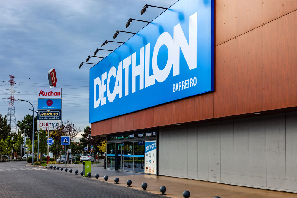 Large blue building signs Houston for a Decathlon retail store located in a shopping center with various shop logos.