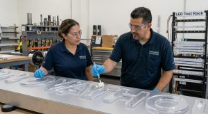 Experts precisely apply bonding agent to acrylic letters for an illuminated sign made by building signs Houston.