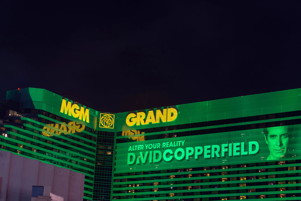 Vibrant retail signs Houston businesses admire on the green MGM Grand hotel with a digital David Copperfield display.