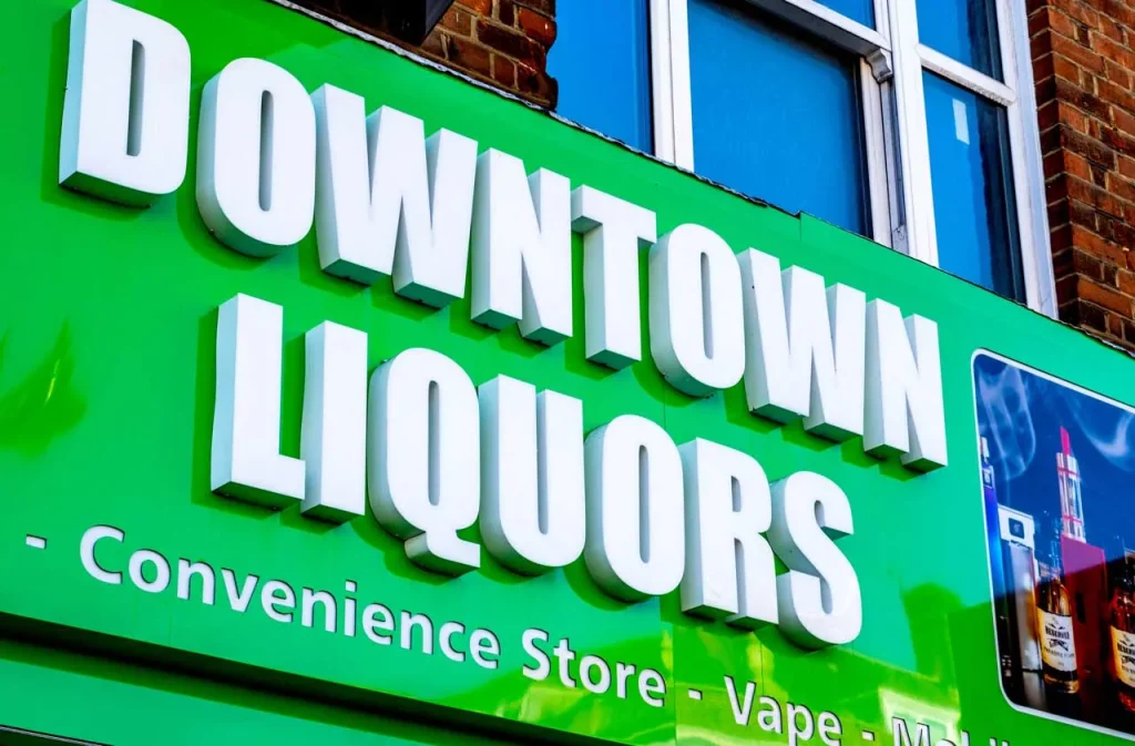 Bold 3D channel letter signs Houston on a green convenience storefront reading Downtown Liquors and Vape.