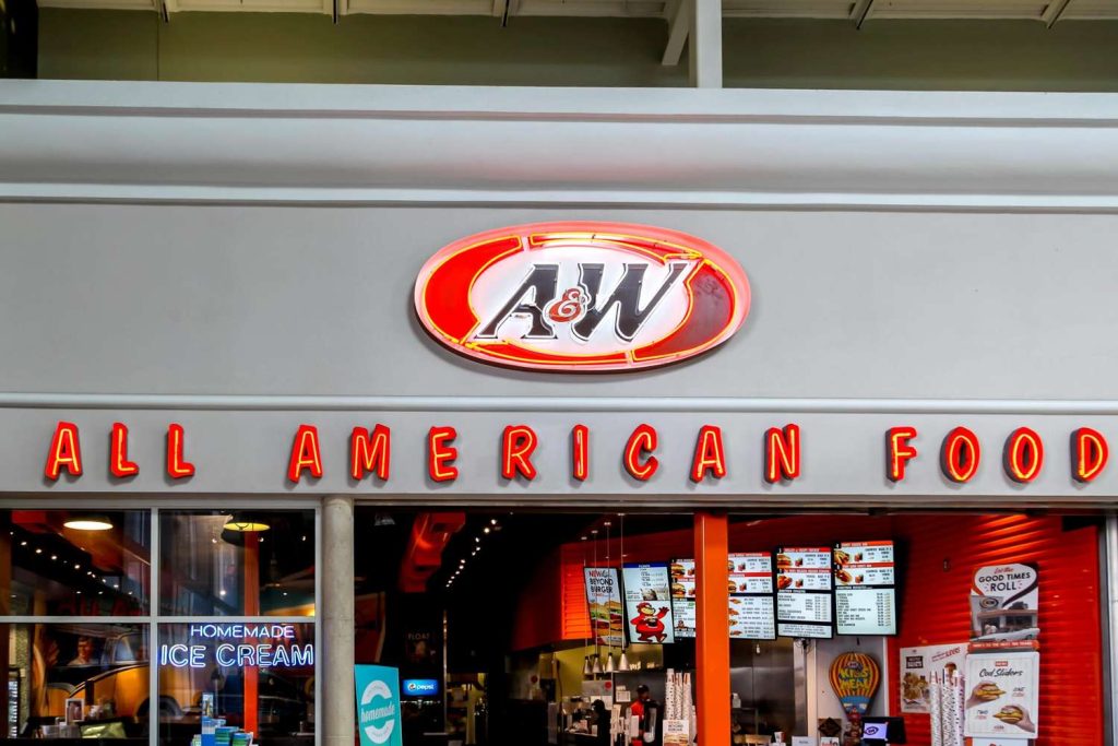 Glowing red neon Houston commercial signs for A&W All American Food located above a restaurant entrance and menu boards. 