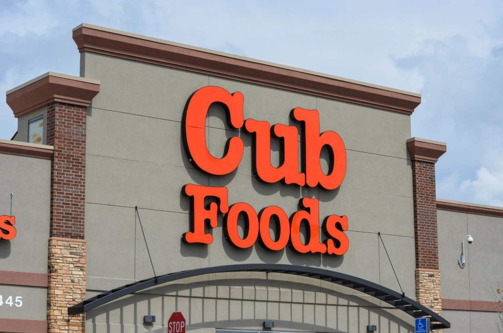 Exterior of a Food Basics storefront featuring green and yellow Houston commercial signs installed on a modern building.