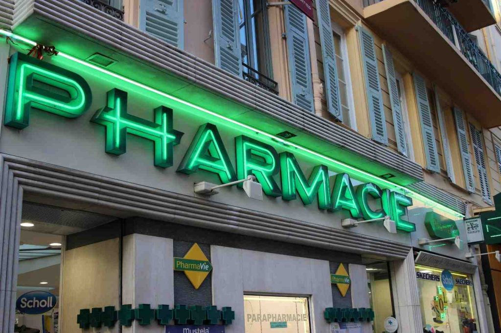 Green neon pharmacie storefront display representing vibrant Houston commercial signs on a European style building.